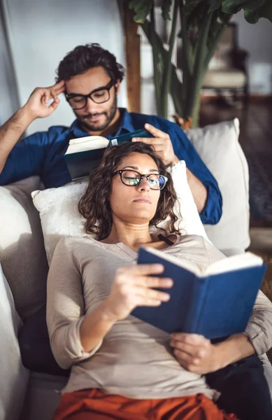 Young couple reading book on couch at home