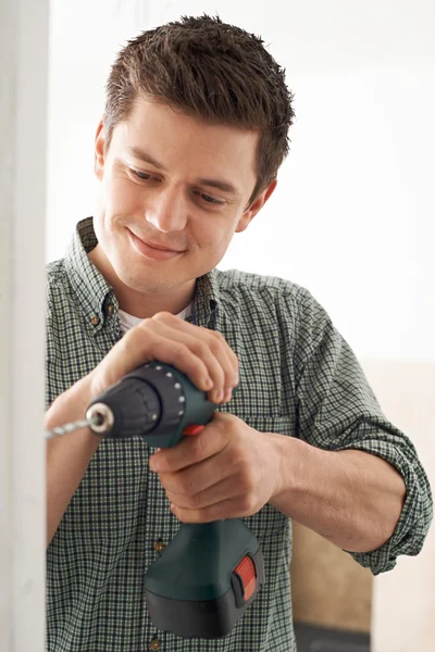 Young Man Using Electric Drill In House Renovation Project
