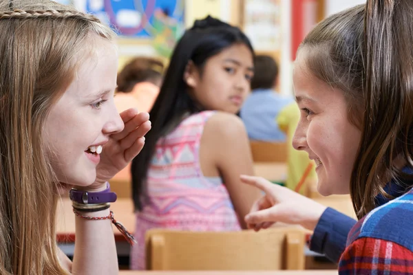 Unhappy Girl Being Gossiped About By School Friends In Classroom