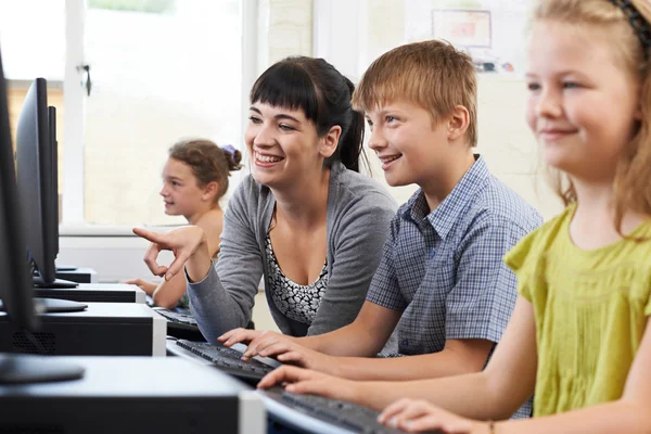 Male Elementary Pupil In Computer Class With Teacher