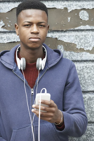 Teenage Boy Wearing Headphones And Listening To Music In Urban S