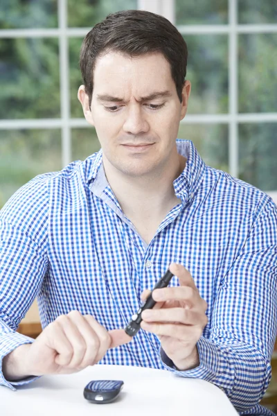 Man Checking Blood Sugar Level At Home