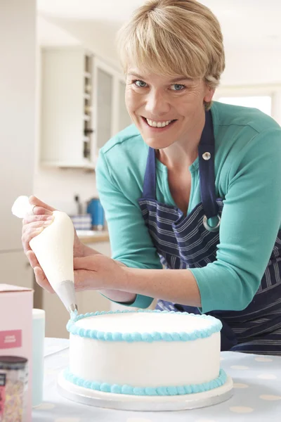 Woman Icing Birthday Cake In Kitchen At Home