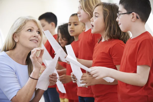 Children In Singing Group Being Encouraged By Teacher