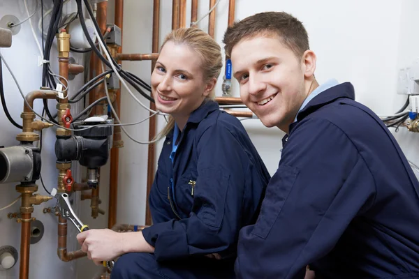 Female Trainee Plumber Working On Central Heating Boiler