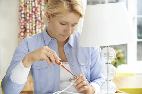 Woman Wiring Electrical Plug On Lamp At Home