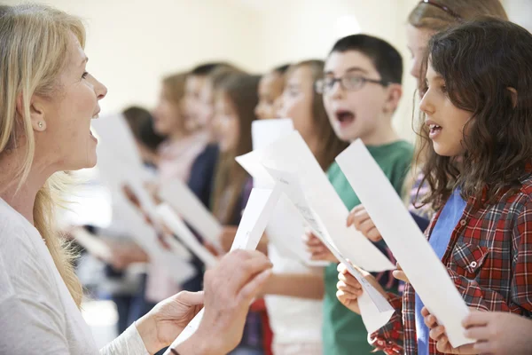 Children In Singing Group Being Encouraged By Teacher