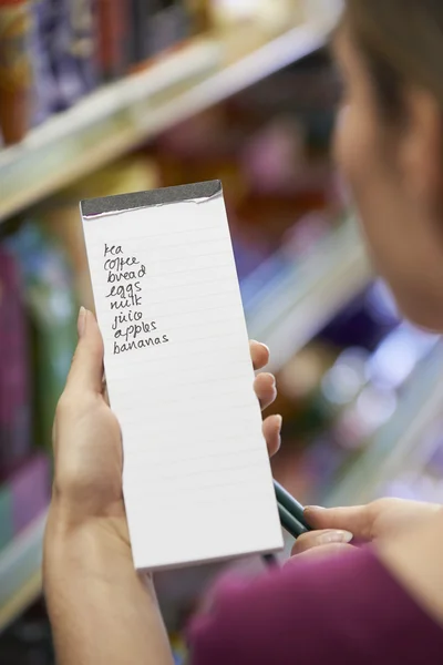 Woman Reading Shopping List In Supermarket
