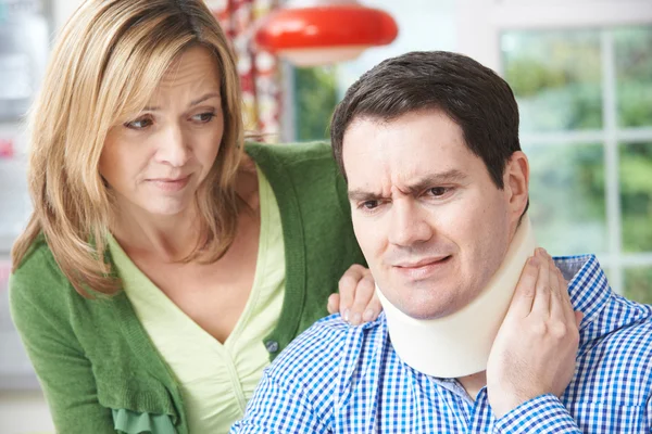 Wife Comforting Husband Suffering With Neck Injury