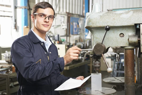 Teenage Apprentice Operating Machinery In Factory