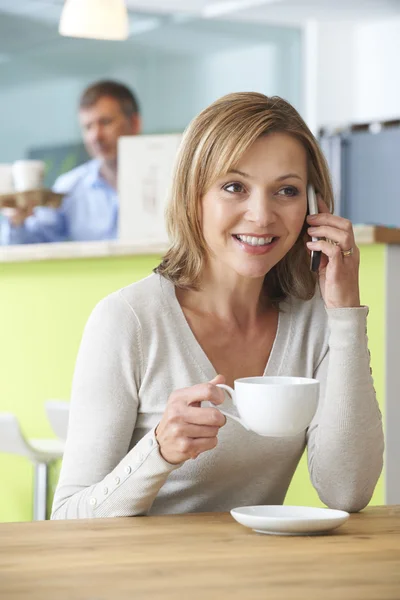 Woman Talking On Mobile Phone In Coffee Shop