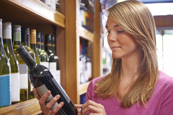 Woman Choosing Bottle Of Red Wine In Supermarket