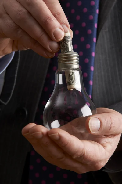 Businessman Putting Dollar Bill Into Light Bulb