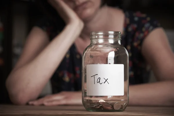 Depressed Woman Looking At Empty Jar Labelled Tax