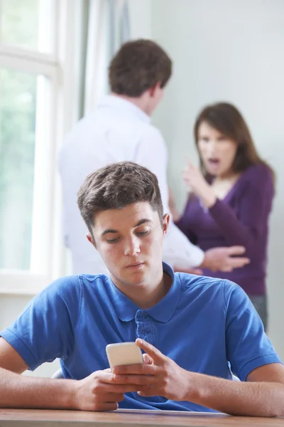 Teenage Boy Texts On Phone As Parents Argue In Background