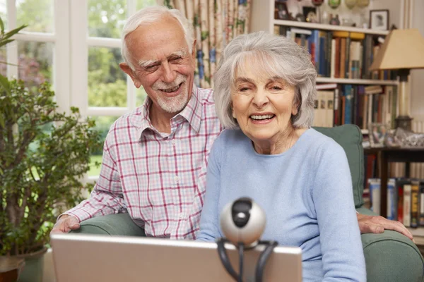 Senior Couple Using Laptop And Webcam To Talk To Family