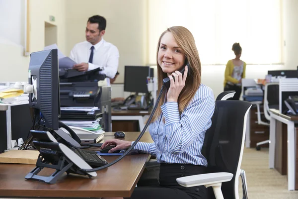 Businesswoman Taking Phone Call In Busy Office