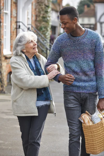 Teenage Boy Helping Senior Woman To Carry Shopping