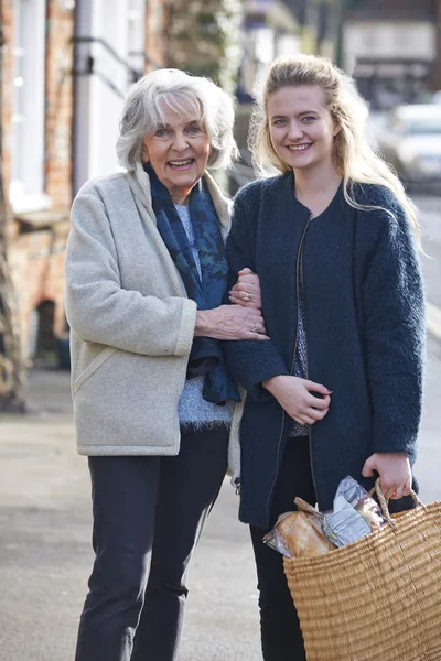 Teenage Girl Helping Senior Woman To Carry Shopping