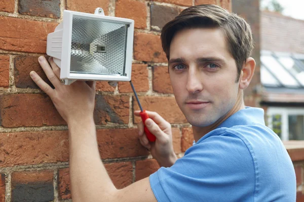 Man Fitting Security Light To House Wall