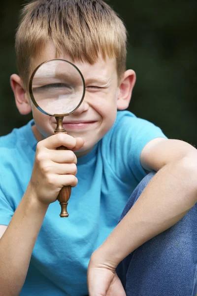 Boy Looking Through Magnifying Glass With Magnified Eye