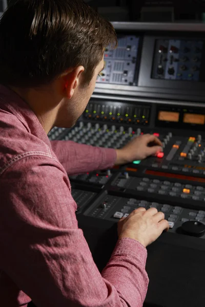 Engineer Working At Mixing Desk In Recording Studio