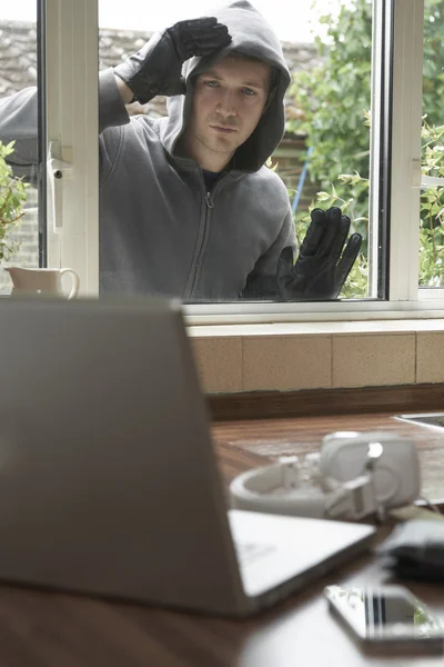 Burglar Looking At Valuables Through House Window