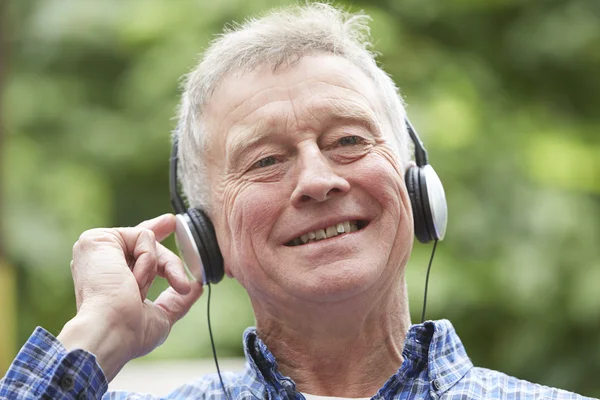 Senior Man Relaxing Listening To Music On Headphones In Garden