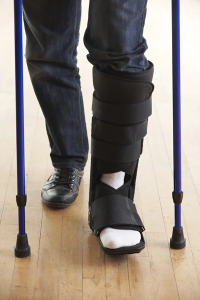 Close Up Of Man Walking With Crutches And Cast