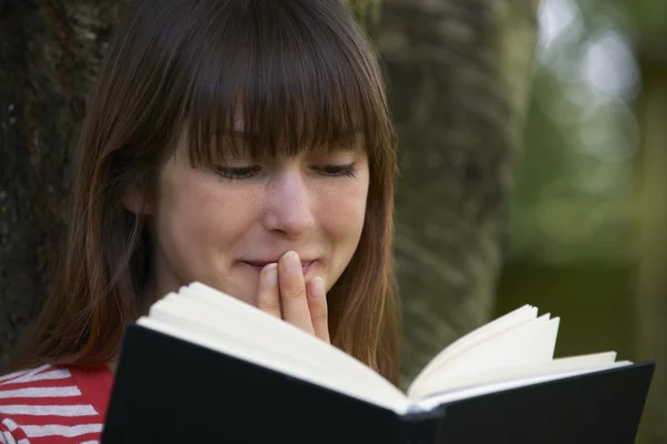 Young Woman Shocked By Reading Novel Outdoors