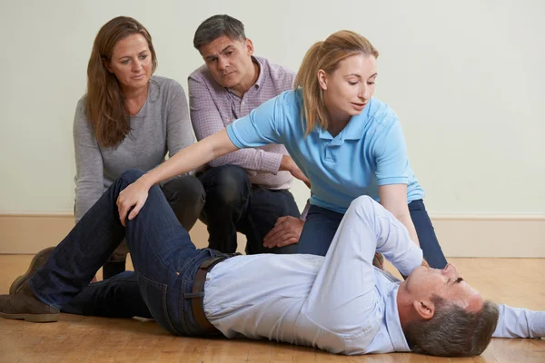 Woman Demonstrating Recovery Position In First Aid Training Clas