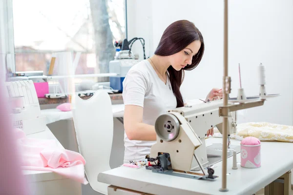 Girl seamstress sew on the sewing machine