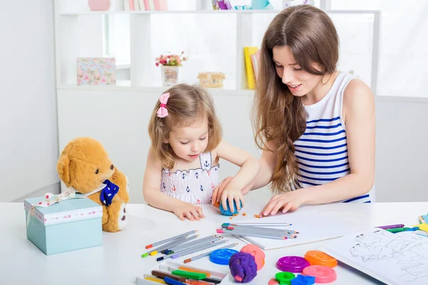 Mother and her little daughter drawing