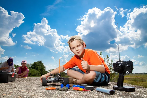 Little boy repaire the radio control car outdoor near field