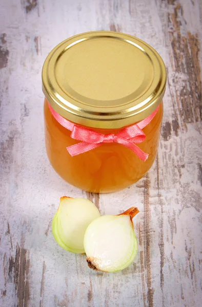 Fresh organic honey in glass jar and onions on wooden background, healthy nutrition and strengthening immunity