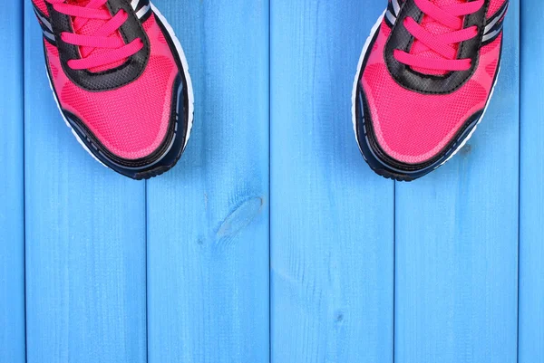 Pair of pink sport shoes on blue boards background, copy space for text