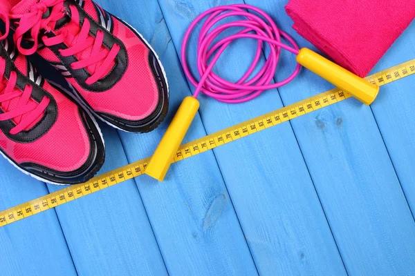 Pair of pink sport shoes and accessories for fitness on blue boards background, copy space for text