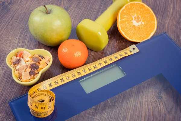 Digital scale with tape measure, dumbbells, fruits, muesli, slimming concept