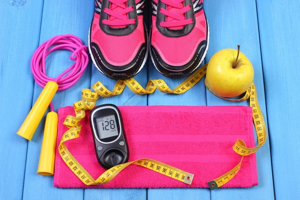 Glucometer, sport shoes, fresh apple and accessories for fitness on blue boards, copy space for text