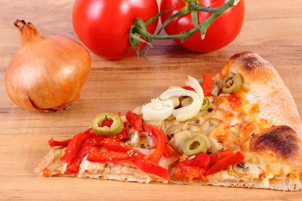 Slice of vegetarian pizza, tomatoes and onion on wooden surface