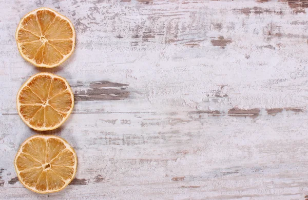 Slices of dried lemon on old wooden background, copy space for text