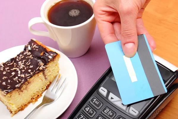 Paying with contactless credit card for cheesecake and coffee in the cafe, finance concept