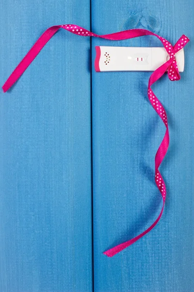 Pregnancy test with positive result wrapped ribbon, expecting for baby, copy space for text