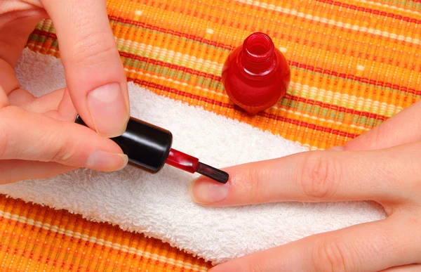 Applying red nail polish, manicured nails of woman
