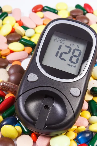 Glucometer with result sugar level and heap of medical pills and capsules, diabetes, health care concept
