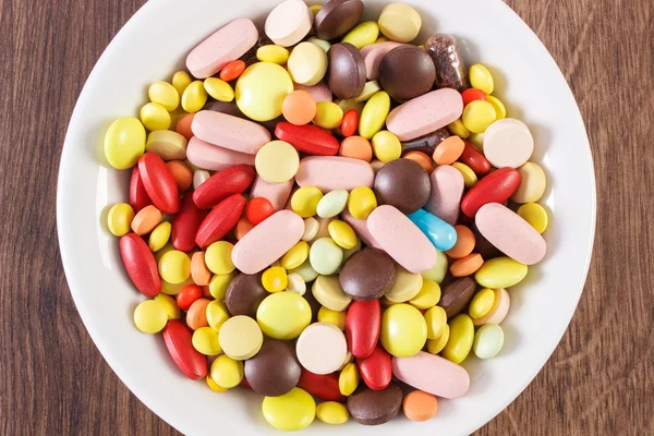Colorful medical pills, tablets and capsules on plate, health care concept