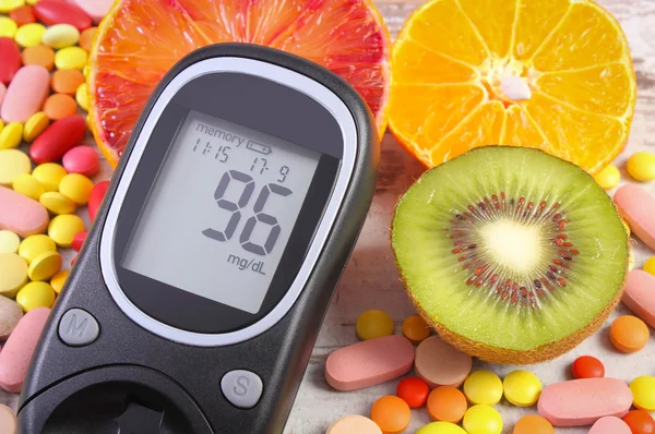 Glucose meter with result, fruits and medical pills, diabetes, healthy lifestyle and nutrition