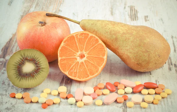 Vintage photo, Fresh fruits and colorful medical pills, choice between healthy nutrition and medical supplements