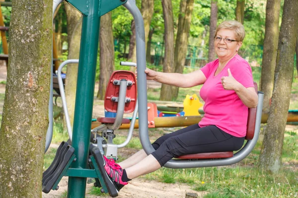 Senior woman exercising lower body on outdoor gym, healthy lifestyle