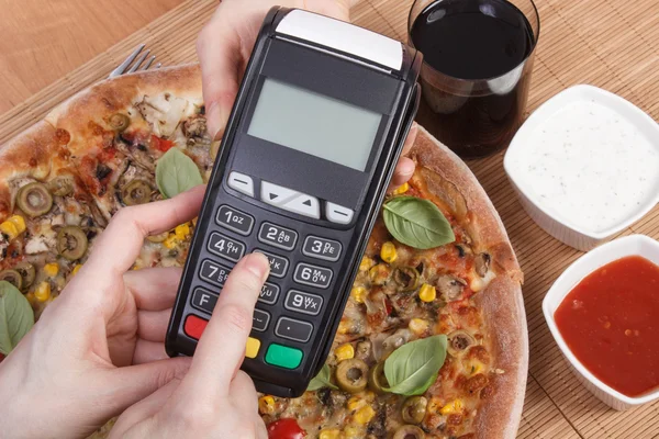 Using payment terminal for paying in restaurant, enter personal identification number, vegetarian pizza